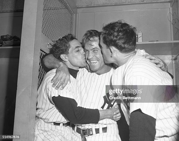 Hank Bauer of the New York Yankees gets kisses from teammates Phil Rizzuto and Yogi Berra after Yanks defeated the Giants 4-3 in today's game to win...