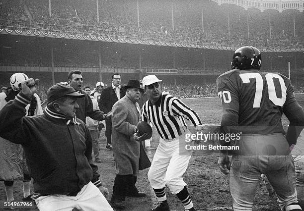 An unidentified official stays between New York Giants' guard Sam Huff and Baltimore Colts' head coach Webb Ewbank during a disagreement in the first...