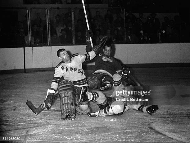 Ranger goalie Lorne Worsley, Red Wing Gordie Howe and Ranger Bill Gadsby all wind up in a pile after Worsely came out of net to clear puck, during...