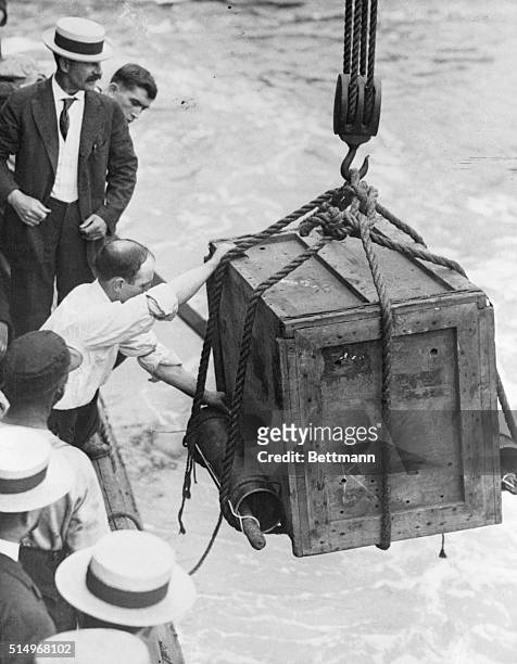 Magician Harry Houdini, in a locked crate, being lowered into the water at the Battery in New York City.
