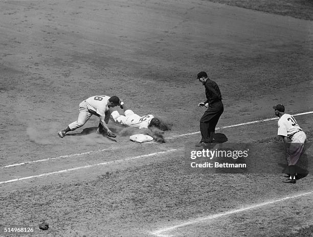 Jackie Robinson, second baseman for the Dodgers, dives back to first base safely when Cincinnati Reds' pitcher Ewell Blackwell tried to pick him off...