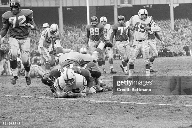 Baltimore Colts fullback Alan Ameche hugs the ball to his chest as he is buried beneath an avalanche of New York Giants tacklers in the NFL Title...