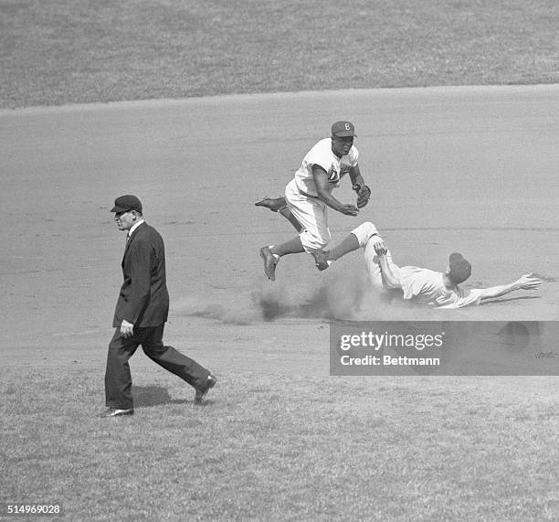 Jackie Robinson leaps into the air in an attempt to make a double play as Hank Sauer slides into second. The action took place during the second...