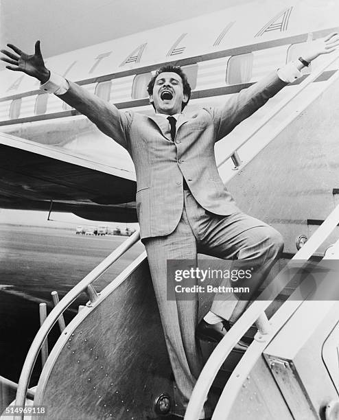 Bursting into song, Italian recording star Domenico Modugno serenades New York after his arrival from Rome aboard an Alitalia Airlines plane. He'll...