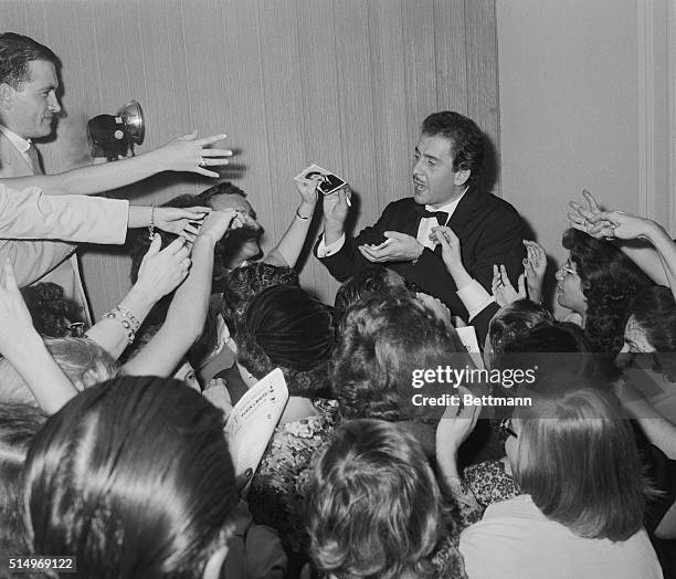 The new rage in singing, Italian singer Domenico Modugno, has his hands full as he hands out autographs after his debut at Carnegie Hall in New York....