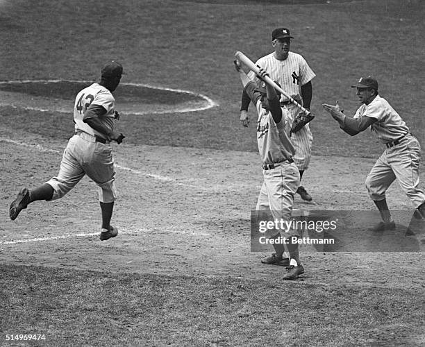 Jackie Robinson of the Brooklyn Dodgers comes home with his team's fifth run, on a passed ball, in the ninth inning of the third World Series game,...