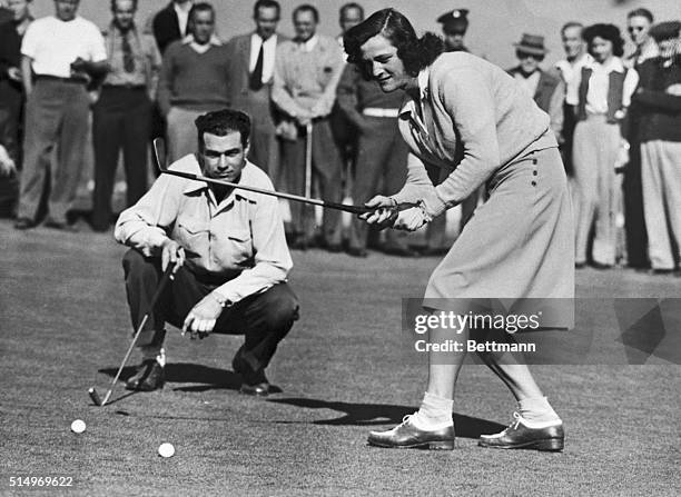 Babe Didrikson Zaharias drops a putt for a par four to halve first hole with Howard Teeter in their golf match at Brookside Park in the Pasadena City...