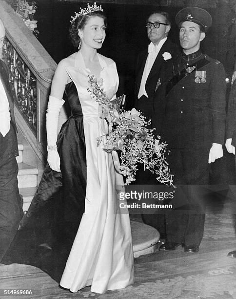 London: Royal Splendor. Wearing an elegant black-and-white satin gown, topped by a jeweled tiara, a radiant Queen Elizabeth II leaves the Empire...