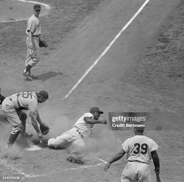 Brooklyn Dodgers Jackie Robinson, shifted to second base for the July 27th game with the Chicago Cubs, slides safely into home plate on a second...
