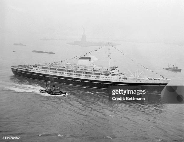 The new Italian liner Andrea Doria glides past the Statue of Liberty as she makes her way to her Manhattan Pier here, upon completion of her maiden...