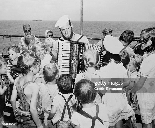 Sort of a pied piper of the pacific is coast guardsman Harry Randall, bearded boatswain's mate 1/c of Seattle, Washington, as the merry tunes he...