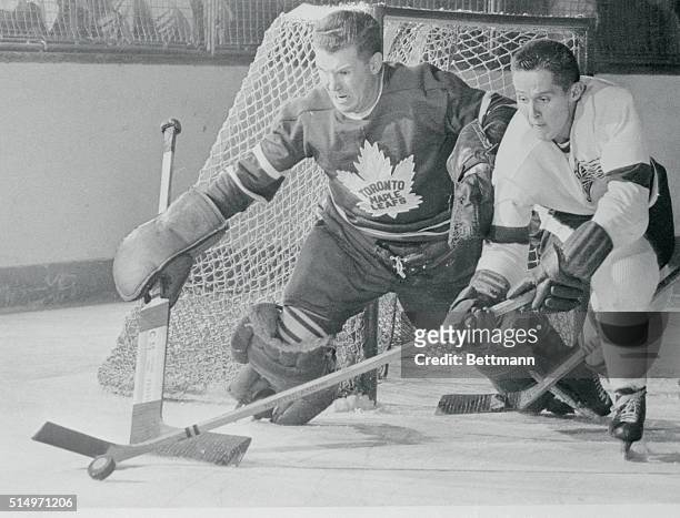 Detroit Red Wing center Earl "Dutch" Reibel out sticks Toronto Maple Leaf goalie Harry Lumley to grab the puck from the Leaf netman in the closing...