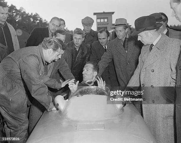 Stirling Moss , Britain's top racing driver, sits in the cockpit of a Mercedes-Benz Grand Prix car he has just tested and tells his impressions to...