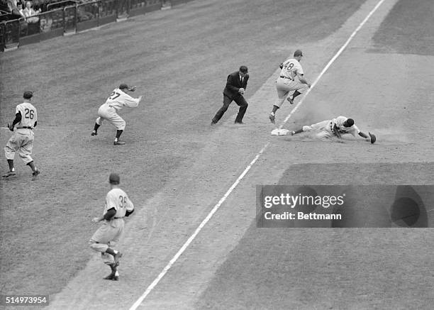 In the 6th inning of today's game between the Brooklyn Dodgers and the Chicago Cubs, played at Ebbet's Field, Robinson of Brooklyn is shown sliding...