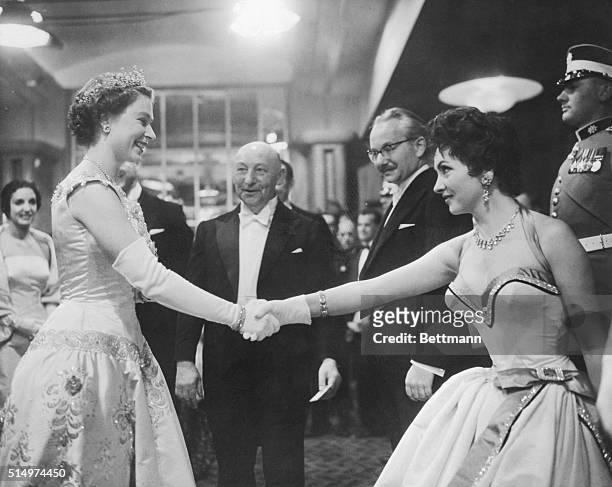 Gina and the Queen. London, England: Gina Lollobrigida curtseys and shakes hands with Queen Elizabeth II at the royal film premiere of Io Catch a...