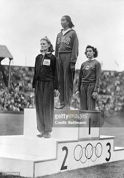 Alice Coachman, of the US, along with the winner DJ Tyler , of Great Britain, and MOM Ostermeyer, of France, stand on a podium at Wembley Stadium to...