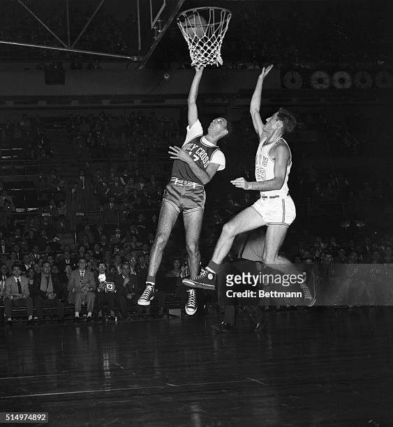 Bob Cousy , of Holy Cross, is shown sinking a basket, as NYU's Jerry Remer 923), rushes to the defense too late, during tonight's game at Madison...