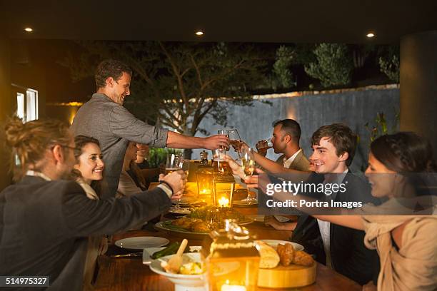 friends toasting wineglasses at dinner table - holiday dinner stock-fotos und bilder