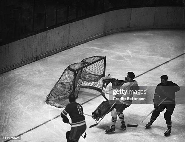 Making a save the hard way, New York Ranger goalie Chuck Rayner is shown flying into Maurice Richard , of the Montreal Canadiens, while Pat Egan , of...