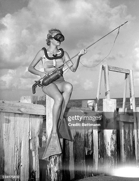 Florida. This is how a fish hunter looks just before she sets out for big game. Dolores Medlin checks her gas gun and spear. She's all decked out...