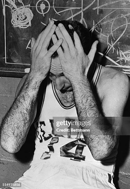 Bob Cousy, of the Boston Celtics, exhausted after game with Philadelphia Warriors, holds his head in his hands in dressing room. He and his teammates...