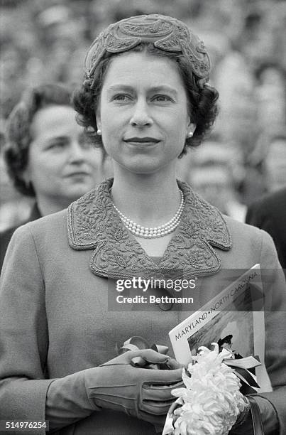 Holding a program and a mums corsage, Queen Elizabeth is shown in her box as she watched the Maryland-North Carolina Football game here, 10/19, at...