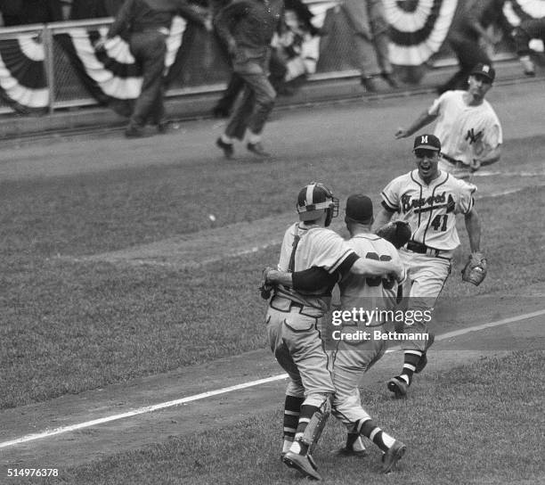 Milwaukee Brave's catcher Del Crandall, , hugs winning pitcher Lew Burdette as Ed Mathews, runs in to join the celebration on the field here, after...