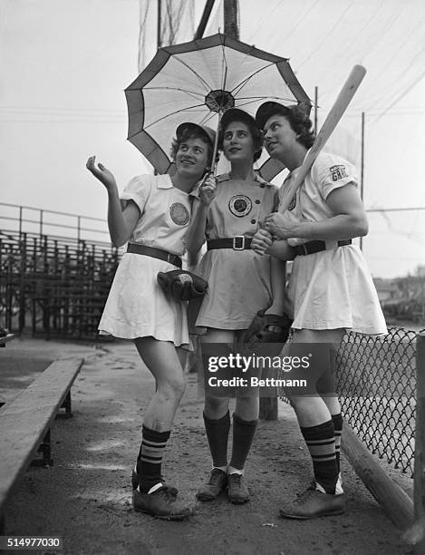 Girl baseball players are shown in uniform, holding an umbrella, a bat and a mitt. Left to right; sisters Joanne Weaver, 15 years old outfielder;...