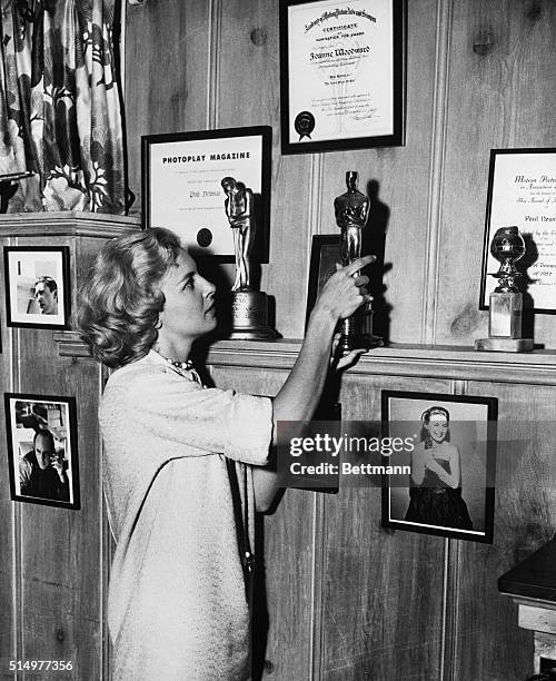 December 13, 1958: Joanne straightens the Oscar she won as the Best Actress of 1957 for it's displayed with other awards she and Paul Newman have...