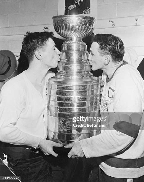 Goalie Terry Sawchuck and Captain Sid Abel of Detroit Redwings kiss the Stanley Cup, won in 8 straight games against Montreal Canadiens.