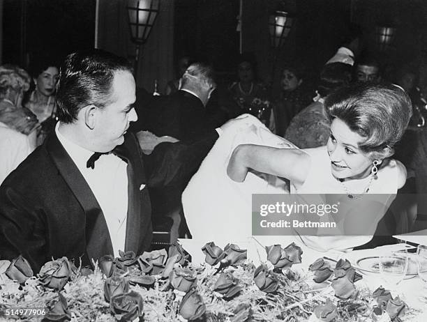 Prince Rainier III of Monaco gives a helping hand to Mrs. Tina Onassis, the beautiful wife of Greek shipping magnate Aristotle Onassis, during the...
