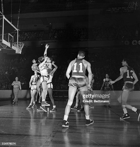 Phenomenal Bob Cousy , of the Boston Celtics, wades his way through three closely guarding New York Knickerbockers to get off an underhanded layup in...