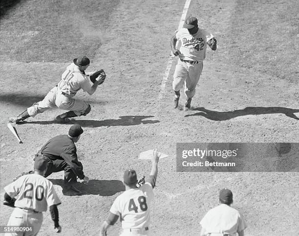 This tenth inning home plate action shows the Dodgers' winning run, which was to trounce the Chicago Cubs, 60 to 5. Photo shows Jackie Robinson as he...