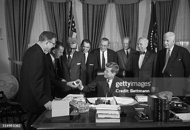 Members of the United States Senate and House of Representatives present President Kennedy with a pair of cuff links after he signed his first bill...