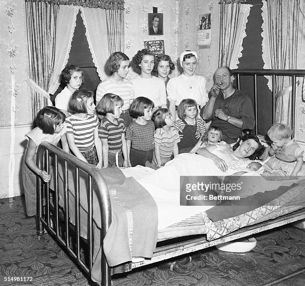 Mr. Lloyd Brooks lights a cigar in celebration of his 14th child - a boy in an all-girl household. Thirteen Brooks daughters gather at the bedside of...