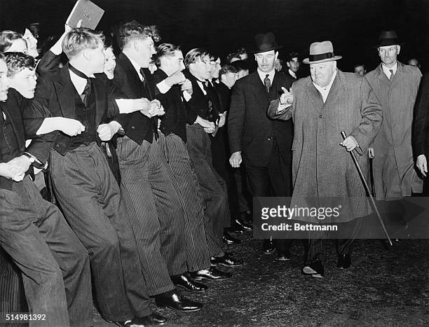 Formally clad Harrow students lock arms to keep their enthusiastic schoolmates from overwhelming Prime Minister Sir Winston Churchill as he paid a...
