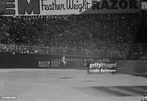 Duke Snider of the Dodgers is shown as he made a sensational, leaping backhand catch of Yogi Berra's long drive to the auxiliary scoreboard at the...