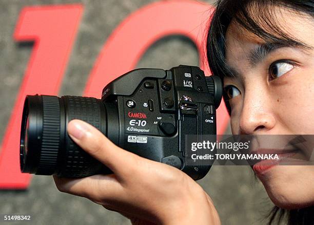 An employee of Japan's Olympus Optical Co., Ltd. Shows off its new digital still camera "CAMEDIA E-10" in Tokyo, 22 August 2000. The new camera...