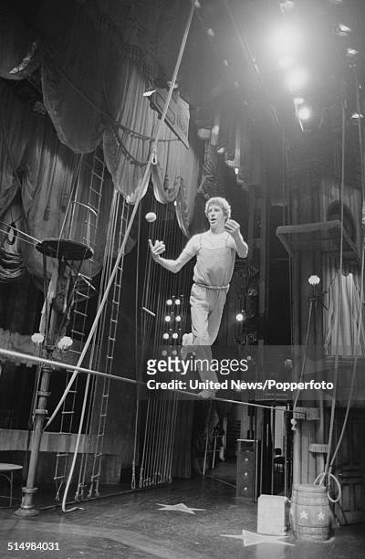 English actor and singer Michael Crawford pictured balancing on a tightrope whilst juggling balls on stage at a rehearsal at the Palladium in London...