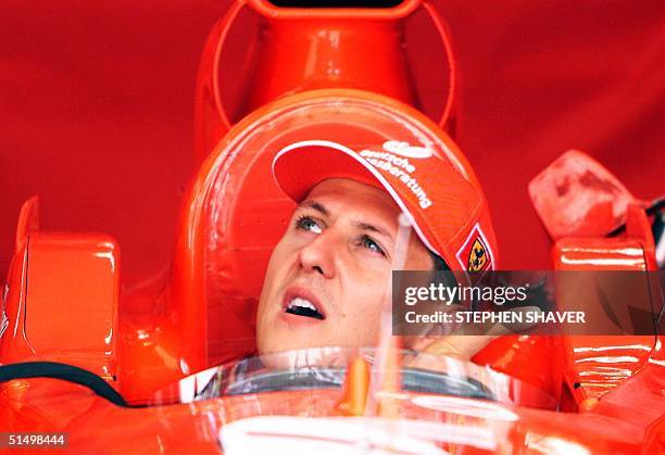 World champion Michael Schumacher talks with a Ferrari mechanic 20 October 2000 prior to free practice at Malaysia's Sepang F1 circuit, two days...