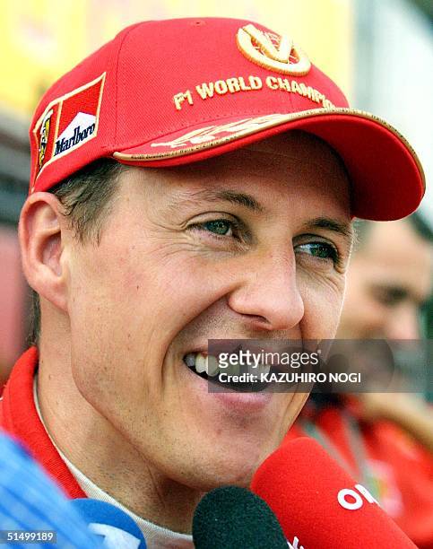 German Formular-One driver Michael Schumacher of Ferrari smiles as he answers questions in a pit after a free practice session at Suzuka circuit, 12...