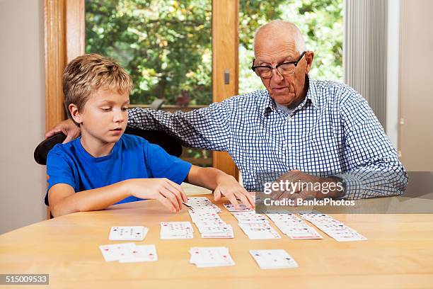 grandfather teaching grandson solitaire playing card game - patience stockfoto's en -beelden