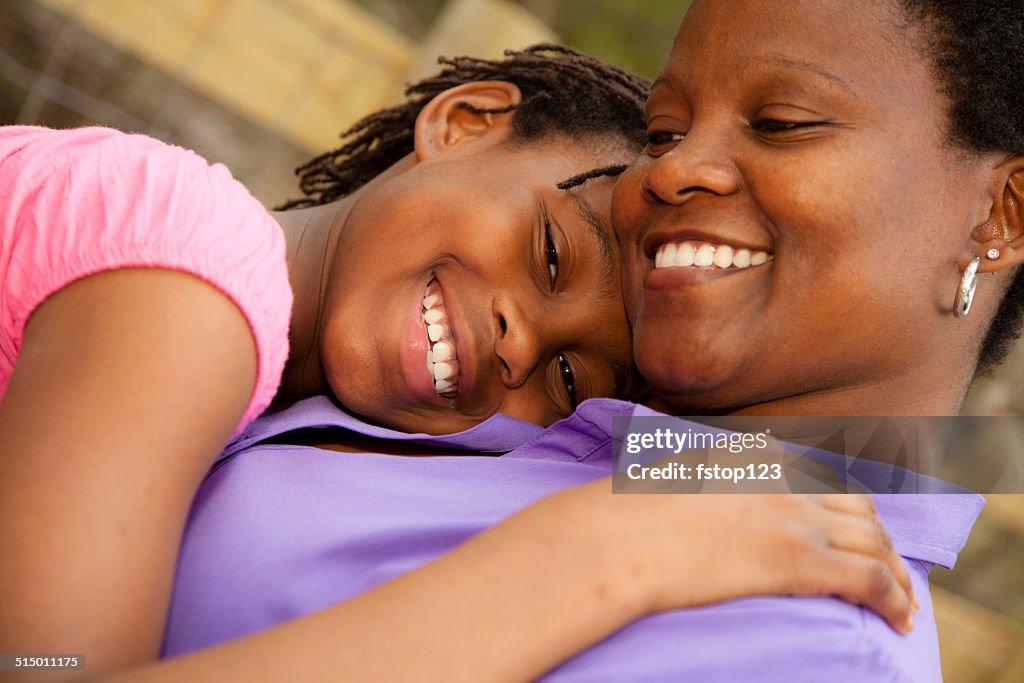 Relationships: African descent mother and daughter hug outside.