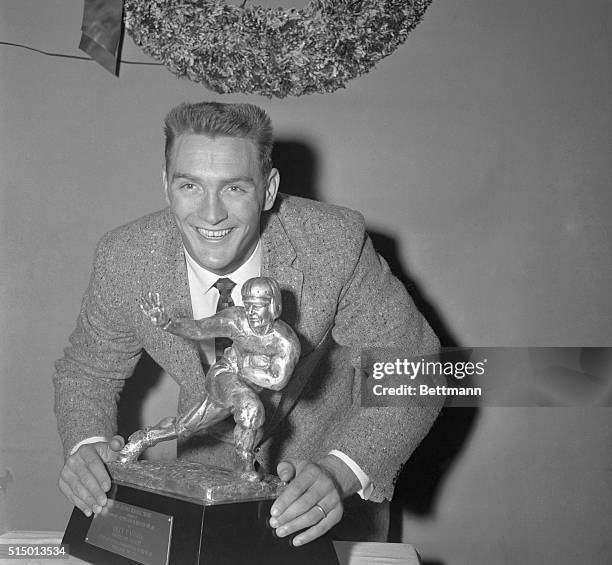 Halfback Billy Cannon of Louisiana State University, standing under a Christmas wreath, gleefully holds the 1959 Heisman Memorial Trophy, which he...