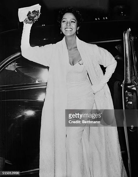 Dorothy Dandridge star of film Carmen Jones, waves to cameras on her arrival at Rivoli Theater for the premiere tonight. The picture, an adaptation...