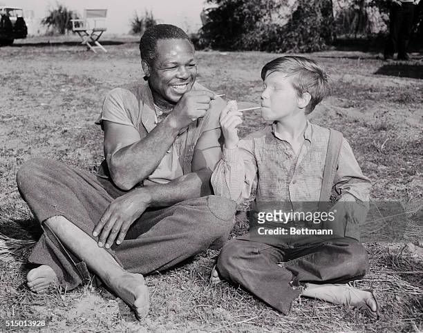 Hollywood: Light heavyweight boxing champion Archie Moore , is shown with actor-youngster Eddie Hodges in a scene from MGM's film version of...