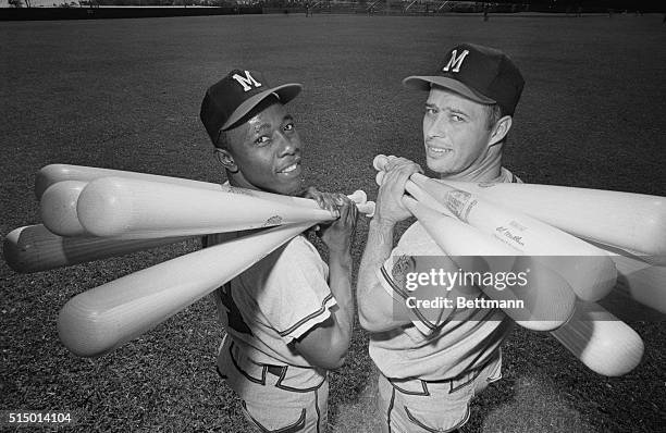 Toting their lumber up to home plate for batting practice are sluggers outfielder Hank Aaron and third baseman Eddie Mathews of the Milwaukee Braves....