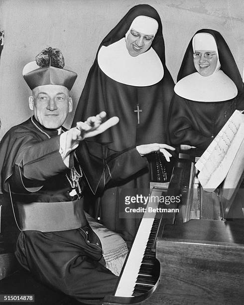 Liberace touch. Kingston, Massachusetts: Archbishop Richard J. Cushing of Boston provides a hearty laugh for Sister Edward Mary and Sister Rosalie as...