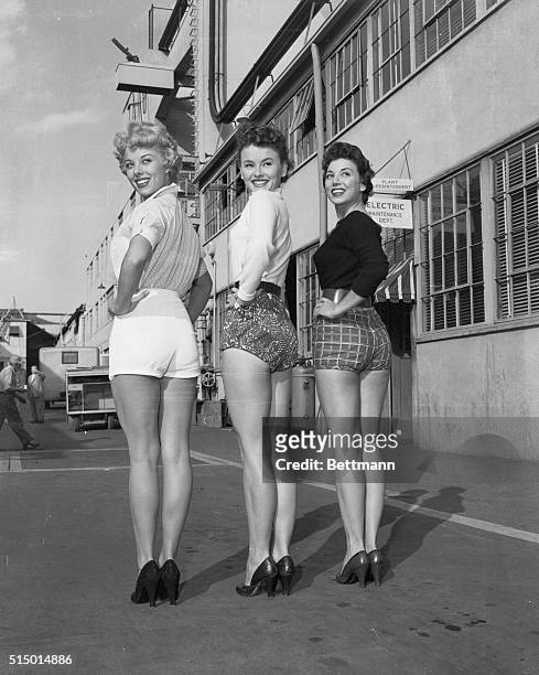 Three shapely but indignant Columbia starlets pause to pose for photographers as they paraded their legs around the studio lot yesterday, to show...