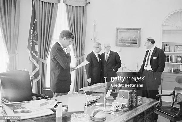 John F. Kennedy, the Chief Executive, scans some papers prior to leaving for the State Department for ceremonies marking 100th anniversary of the...